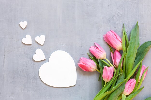 Bouquet  of pink tulips and wooden hearts pattern