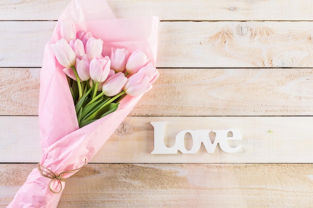 Bouquet of pink tulips wrappen in pink paper.