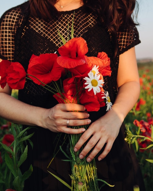 Букет цветов мака в женской руке на закате крупным планом
