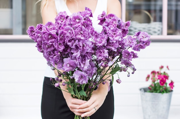 Bouquet of purple lilac delphinium in women's hands on the street