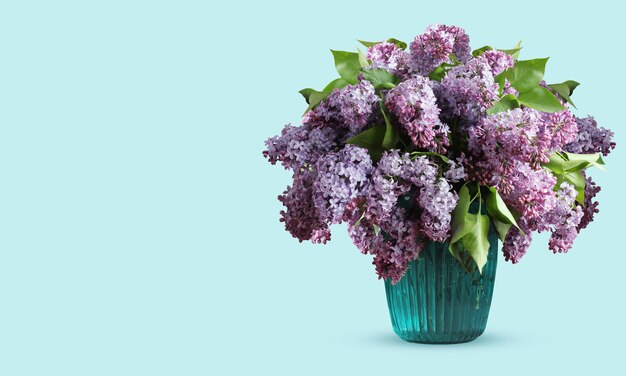 Bouquet of purple lilacs in blue glass vase with copyspace