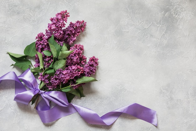 Bouquet of purple lilacs on light table in top view