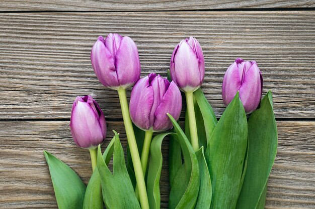 Foto bouquet di tulipani viola su una superficie in legno vista dall'alto