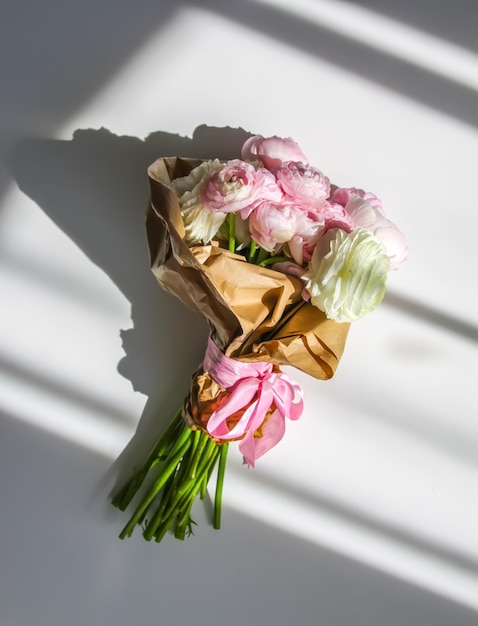 Bouquet of Ranunculus beautiful delicate flowers Floral decor Bright sunlight and shadows on a white surface