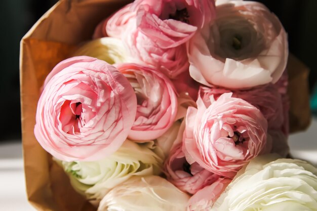 Bouquet of Ranunculus beautiful delicate flowers Floral decor Bright sunlight and shadows on a white surface