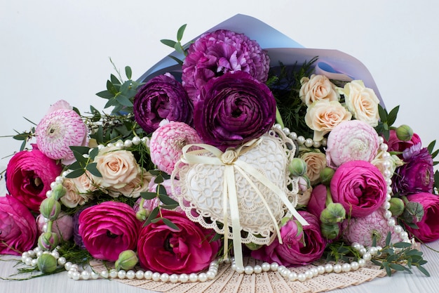  a bouquet of ranunculuses, roses, pearl beads and a heart of lace