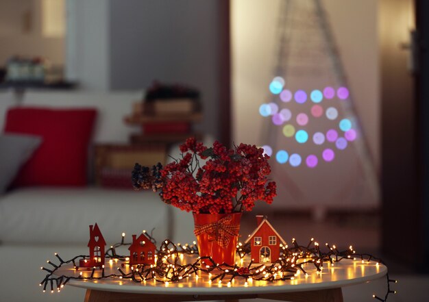 Photo bouquet of red berries with light garland on a table