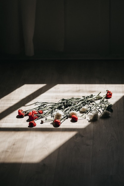 A bouquet of red flowers on a wooden floor