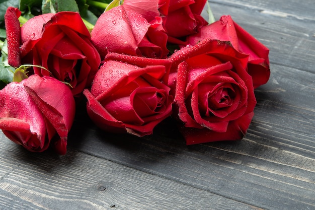 Foto mazzo del fiore della rosa rossa sulla tavola di legno scura.