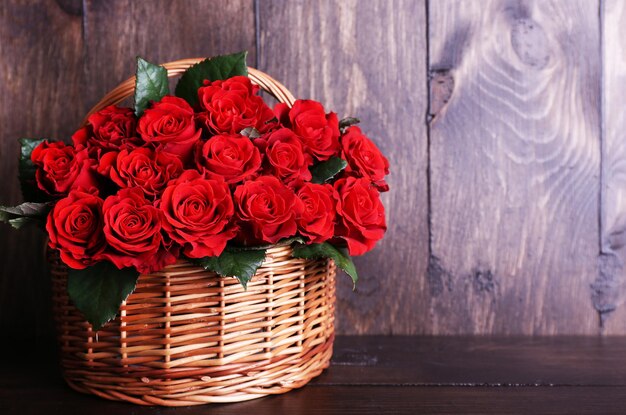 木製の背景のバスケットに赤いバラの花束