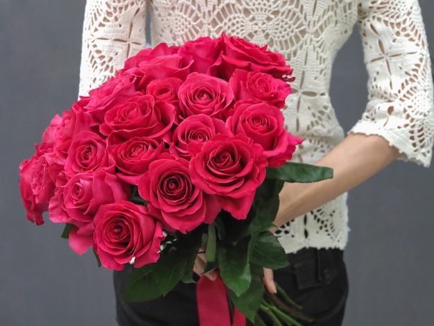 Bouquet of red roses behind her back