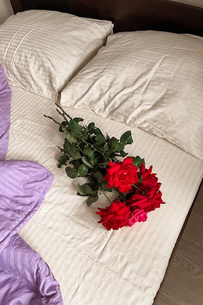 Photo a bouquet of red roses lies on the whitelilac bed linen aesthetic minimalism greeting card with good morning