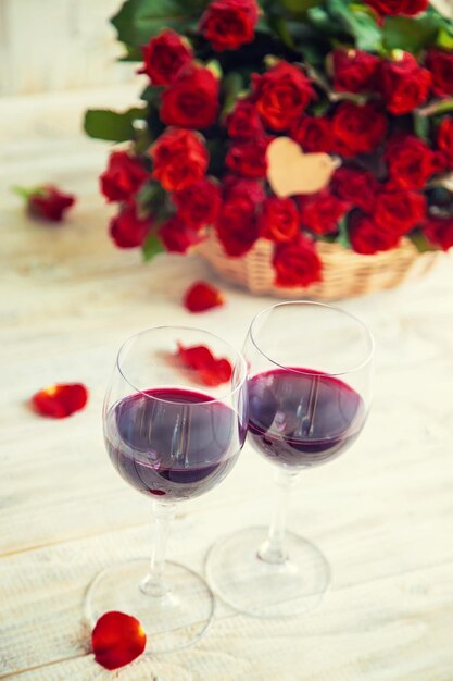 A bouquet of red roses and red wine in glasses Valentine's Day Selective focus