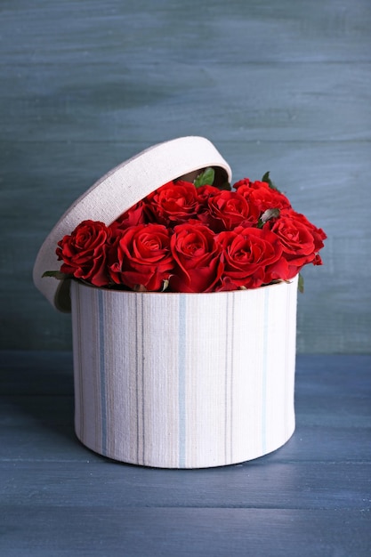 Photo bouquet of red roses in textile box on wooden background