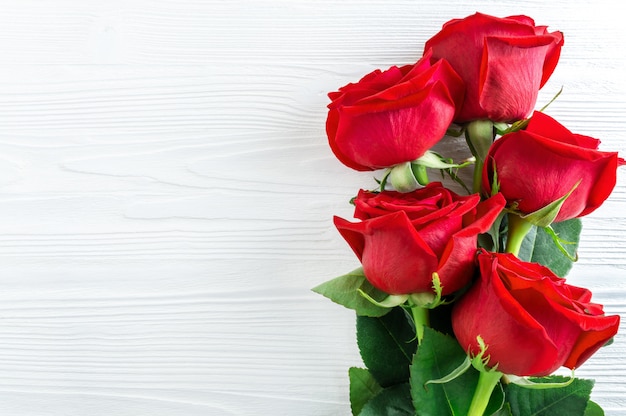 白い木製の背景に赤いバラの花束。