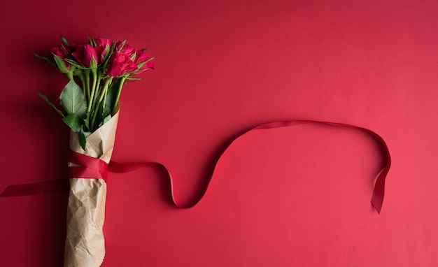 보라색 판지 배경 복사 공간 상위 뷰에 장식 리본이 있는 빨간 장미 꽃다발