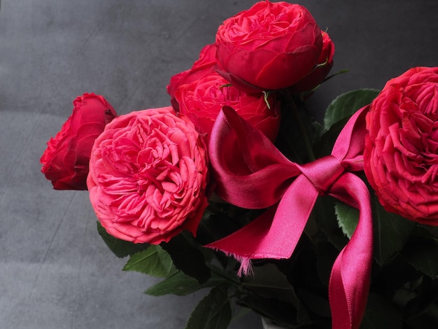 A bouquet of red roses with a pink ribbon.