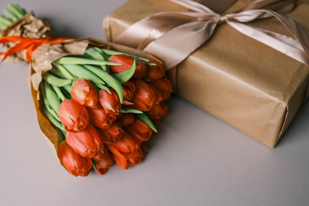 赤いチューリップの花束と 弓の祭りのコンセプトのギフトボックス