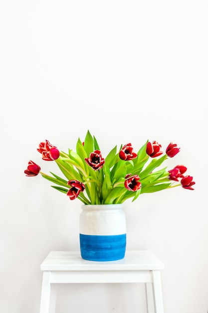 A bouquet of red tulips in a vase on the table in the modern living room Beautiful spring concept