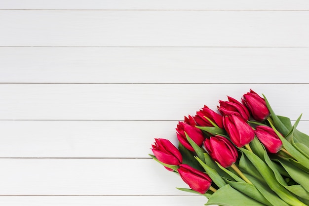 Букет красных тюльпанов на белом деревянном фоне вид сверху копией пространства