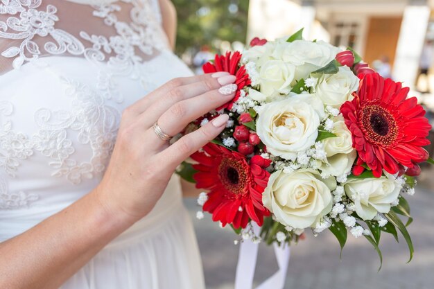 Bouquet of red and a white roses in the bride's hands Closeup