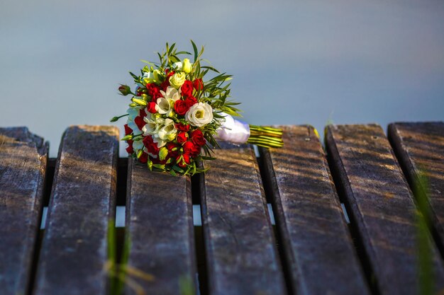 Bouquet of red and white roses flowers on the wooden bridge with evening sun