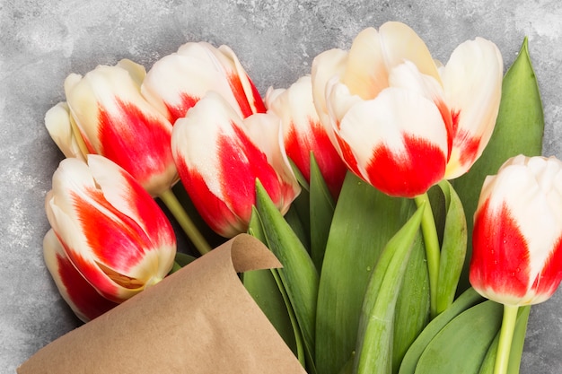 Bouquet of red-white tulips in kraft paper on a light background. Top view.