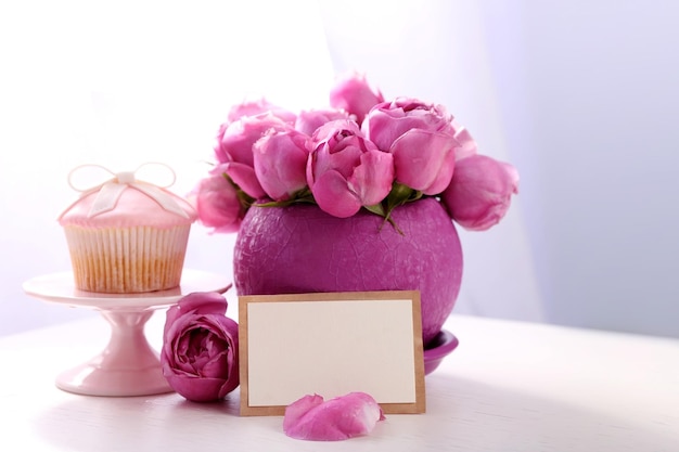 Bouquet of roses gift card and cake on table