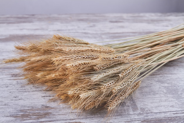 Bouquet of rye and wheat spikelets on white wooden desk