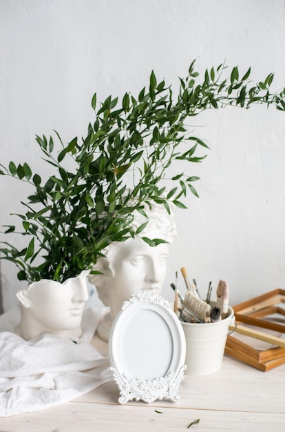 Bouquet of snowdrops in modern ceramic vase with mockup frame in scandinavian interior