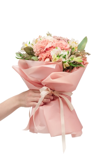 Bouquet of  soft pink flowers in pink wrapping paper in woman hands isolated on white surface