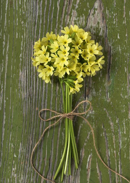 Photo bouquet of spring cowslip flowers on a rustic green wooden background still life top view