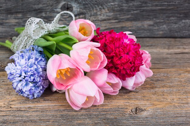 Bouquet of spring flowers decorated with ribbon on old wooden table. Soft focus