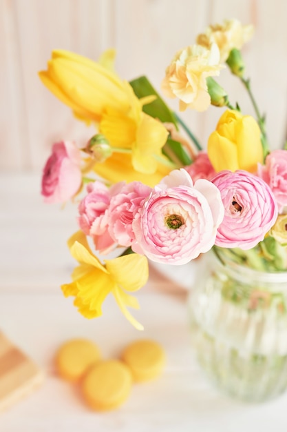 Bouquet of spring flowers: tulips, carnations, ranunculi and daffodils in vase on table. Mother's day greeting 