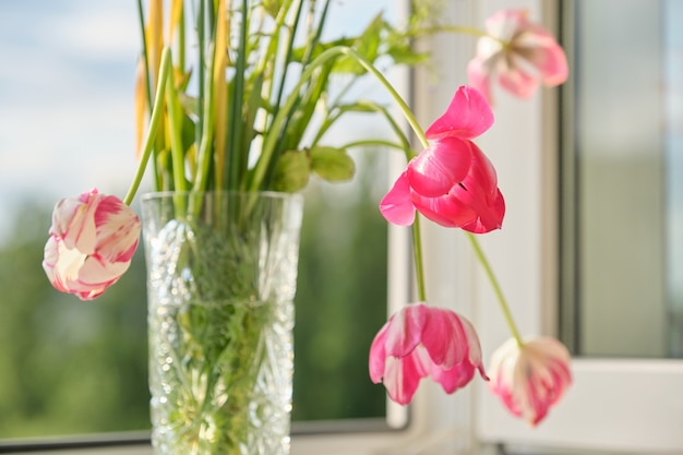 春の花のチューリップと窓の上に花瓶の白い水仙の花束