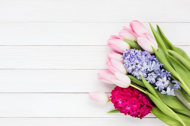 Bouquet of spring flowers on white wooden background with copyspace. Top view