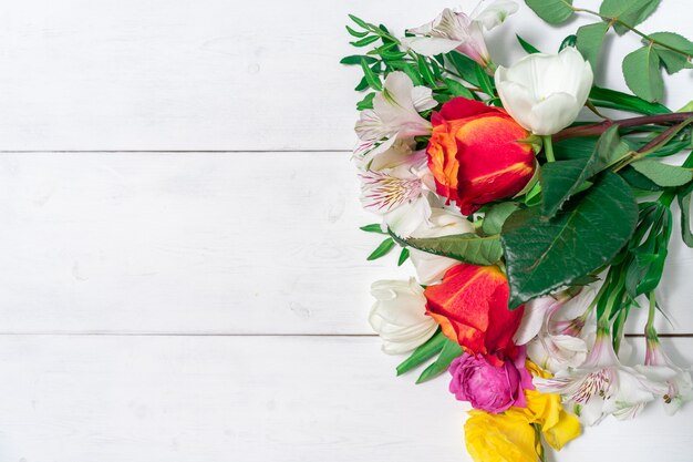 Bouquet di fiori primaverili su uno sfondo di legno bianco con posto per il testo. mock up con copia spazio