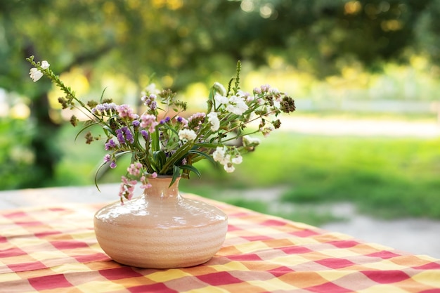 Bouquet di fiori estivi in vaso di ceramica sul tavolo sul terrazzo. arredamento accogliente del cortile del patio.