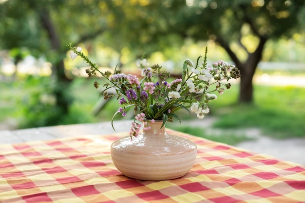 テラスのテーブルの上の陶製の花瓶の夏の花の花束