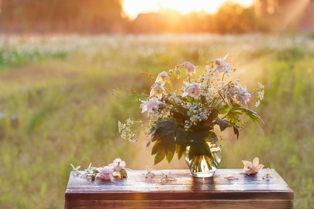 屋外の日光の下でガラスの花瓶に夏の花の花束