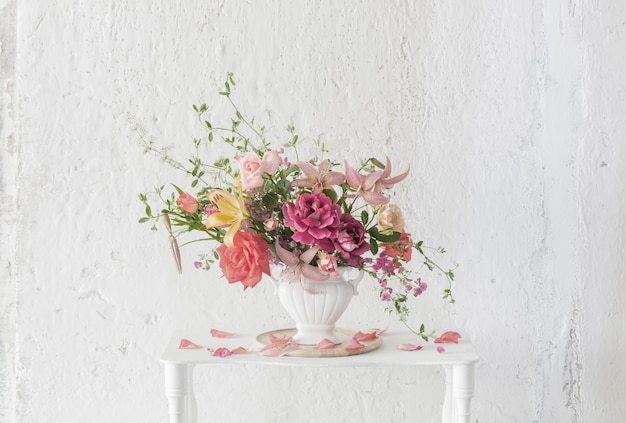 Bouquet of summer flowers in vase on vintage white wooden shelf on white background