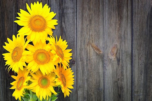 木製の壁の背景にひまわりの花束