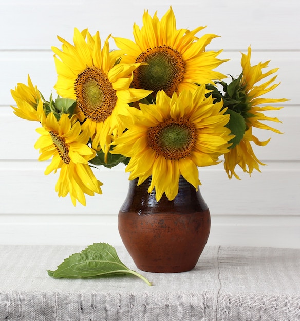 Bouquet of sunflowers in a rustic clay jug on the table