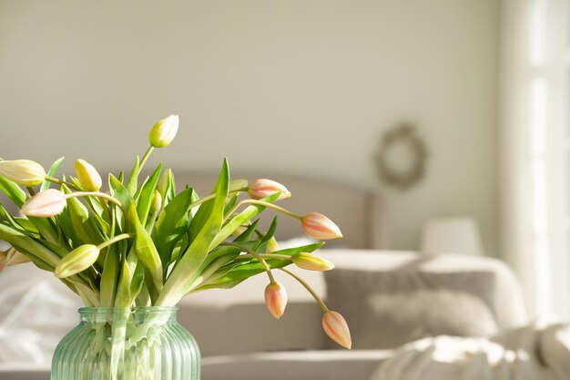 A bouquet of tulips in a beautiful vase at home in a bright modern interior on a wooden table