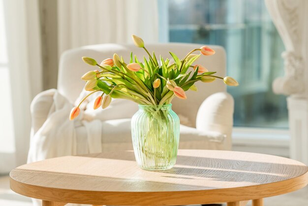 A bouquet of tulips in a beautiful vase at home in a bright modern interior on a wooden table