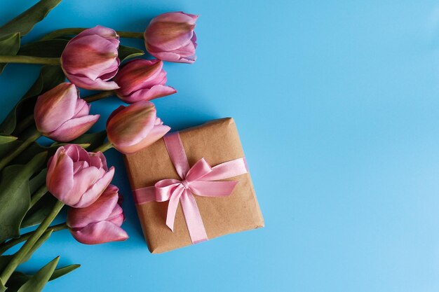 A bouquet of tulips and a gift box on a blue background