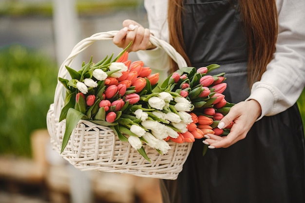 Bouquet of tulips in a guy. Guy and girl in a greenhouse. G.ardeners in aprons.