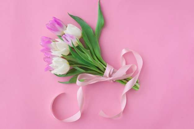 Bouquet of tulips on a pink pastel background.