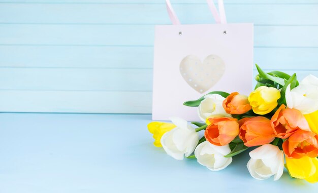 Photo a bouquet of tulips with a heart on a blue background.