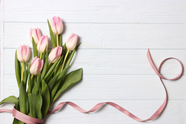 A bouquet of tulips on a wooden background top view spring background